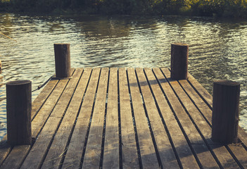 Small dock with no people in a lake during summertime. Four small pillars and water in the picture. - 193944350