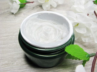 Fototapeta na wymiar cosmetic cream for face care and white sakura flowers