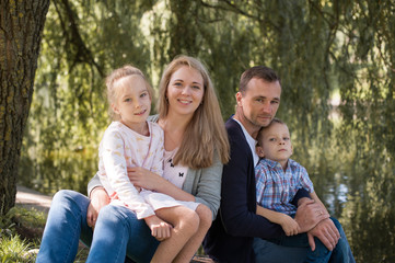 Fototapeta premium Mom and dad playing with their handsome son and daughter - Family and children outdoors in the park - Young beautiful family posing for the photographer