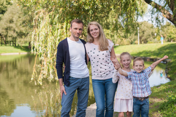 Mom and dad playing with their handsome son and daughter - Family and children outdoors in the park - Young beautiful family posing for the photographer