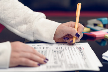 Woman fills the tax form, working with tax documents.Form 1040 Individual Income Tax return form. United States Tax forms 2017/2018.