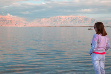 Fototapeta na wymiar Adult woman staring at the distance in Dead Sea, Israel..Landscape Dead Sea Coast, rest and treatment at the Dead Sea resorts.