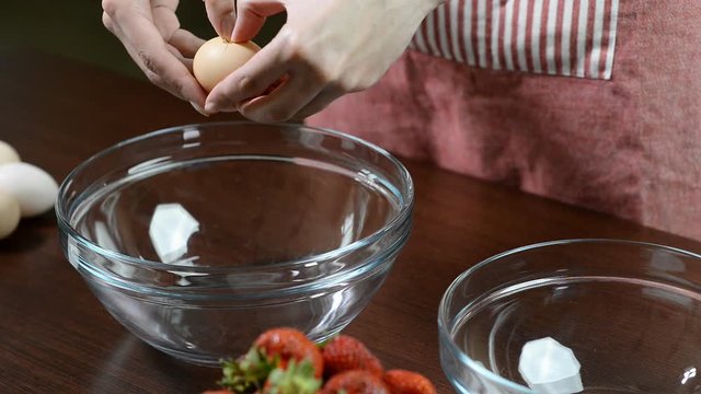 Woman hands breaking an egg to separate egg white and yolks