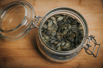 Pumpkin seeds in glass on wooden background. Healthy