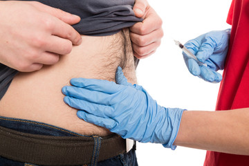 Close-up of female doctor giving injection to male patient belly.