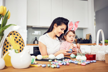 Happy mother and child painting Easter eggs