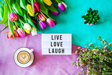 Live love laugh written in lightbox with spring flowers from above