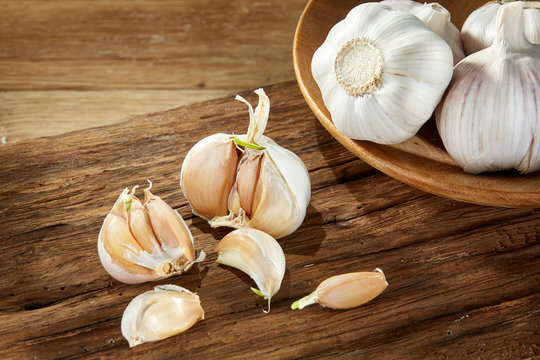 Garlic close up on wooden plate on rustic background, shallow depth of field, selective focus, macro