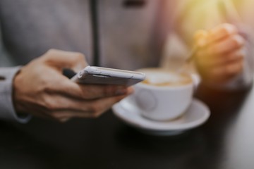 hand with mobile phone and coffee mug