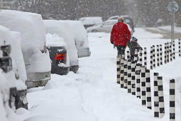 Winter. People walk on a very snowy sidewalk and road. People step on an icy pathway, icy sidewalk. Uncleaned streets and roads. 