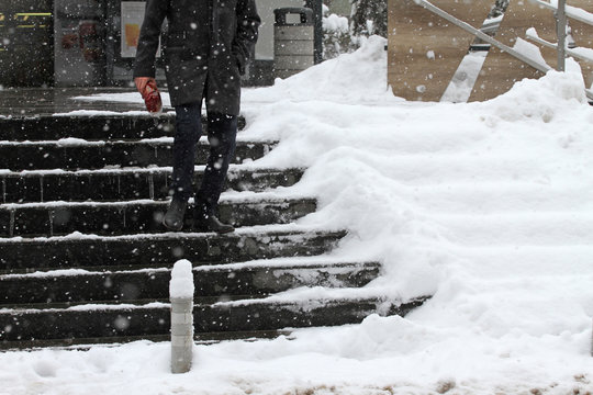 Winter. Stairs. People walk on a very snowy stairs. Uncleaned icy stairs in front the buildings, slippery stairs