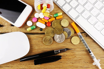Online medical consultation or online pharmacy concept with colourful pills, smartphone and computer keyboard on wooden table
