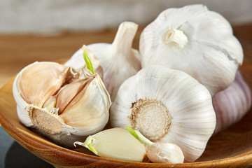 Garlic close up on wooden plate on rustic background, shallow depth of field, selective focus, macro