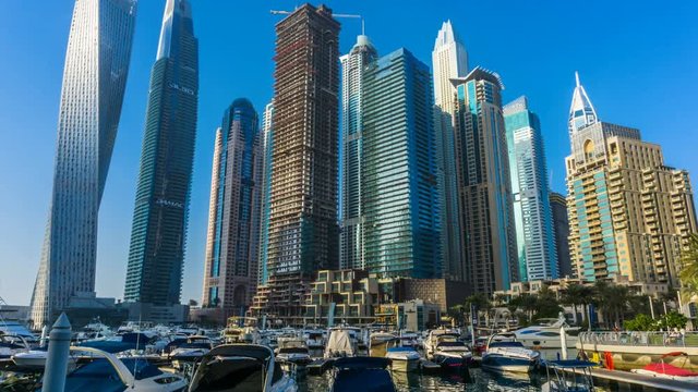 sunset time view from promenade Dubai Marina modern towers and floating yachts and boats timelapse