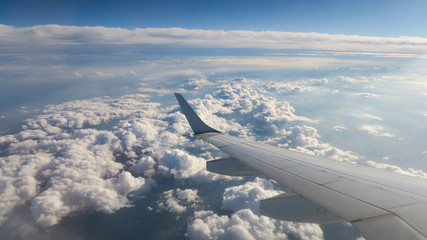 Wide Panorama view out of flying plane - Aircraft's wings in front of white puffy clouds as far as...