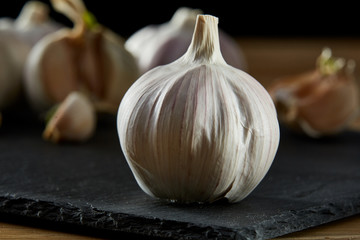 Garlic close up on wooden plate on rustic background, shallow depth of field, selective focus, macro