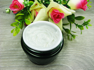 Obraz na płótnie Canvas cosmetic cream for face care and rose flowers