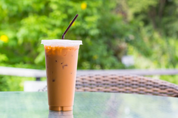 iced milk tea in plastic cup on glass table