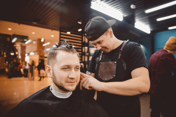 Barber shop. Man with wife in barber's chair, hairdresser Barbershop styling his hair