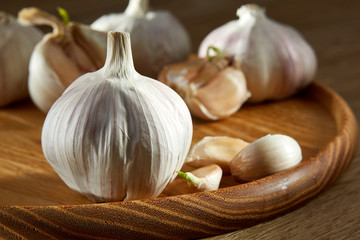 Garlic close up on wooden plate on rustic background, shallow depth of field, selective focus, macro
