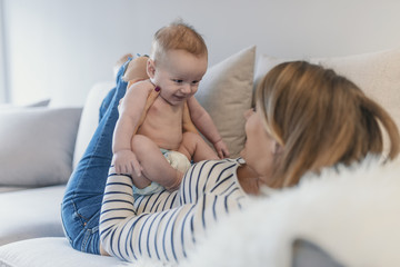 Portrait of beautiful mom playing with her 4 months old baby in bedroom