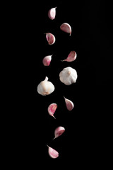 Falling Garlic bulbs and pink cloves of garlic isolated on black background - 193956304