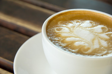 A cup of Cappuccino coffee in a white cup on wooden background