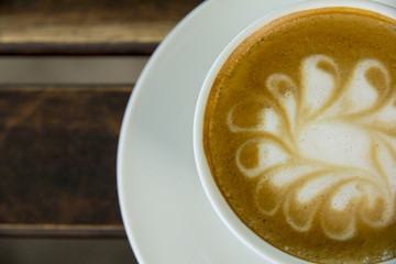 A cup of Cappuccino coffee in a white cup on wooden background