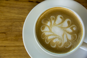 A cup of Cappuccino coffee in a white cup on wooden background