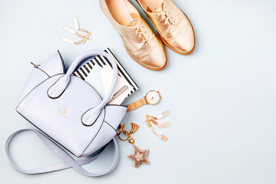 Cute blue ladies bag, stylish golden shoes and  feminine accessories . Flat lay, top view. Spring fashion concept in pastel colored