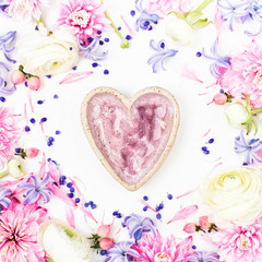 Beautiful floral arrangements. Frame made of ranunculus, chrysanthemum and other flowers with ceramic heart on white background. Flat lay, top view.