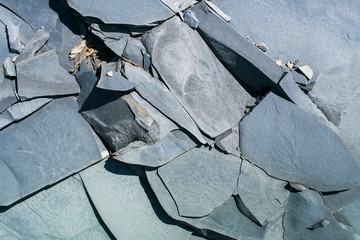 Natural gray stony uneven background consisting of pieces of splited mountain slate.