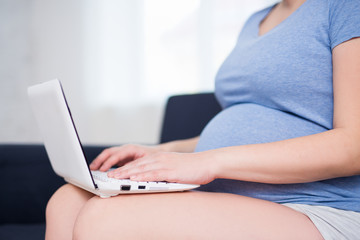 Naklejka premium close up of pregnant woman working with laptop