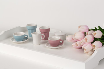 Tazas de café y vajilla con tulipanes rosas.