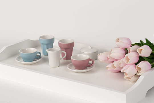 Tazas de café y vajilla con tulipanes rosas.