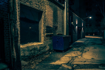 Dark empty and scary urban city street.alley with a vintage warehouse loading dock and a garbage...