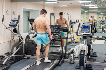 Young sexy male bodybuilder athlete, trains in the gym, using sports equipment and fitness equipment to improving health and beauty of the body