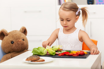 Little preschool girl having a healthy snack with her toy bear