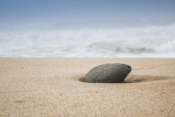 Fototapeta na wymiar single stone in sand on the beach