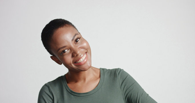 black woman with a short haircut in studio shootsmiling and wearing dress
