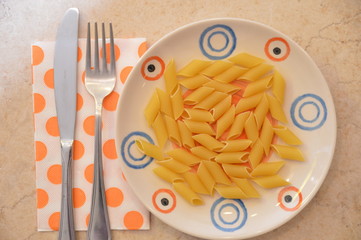 pasta italiana penne mignon in piatto con posate