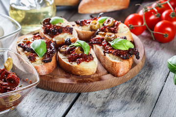 Appetizer bruschetta with sun-dried tomatoes, olives and mozarella.