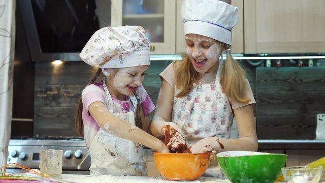 Kids having fun in the kitchen play and mixing chokolate dough with hands.