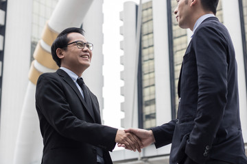 Successful negotiating business concept, Businessmen shaking hands after finishing meeting or setting  goals and planning way to success in front of building .