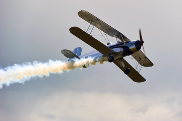 Vintage single engine propeller biplane aircraft flying against sky 