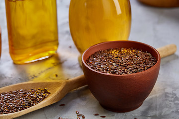 Flax seeds in bowl and flaxseed oil in glass bottle on wooden background, top view, close-up, selective focus