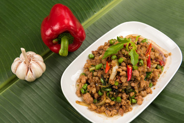 stir fried pork with basil  in white dish on banana leaf