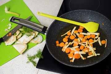 Fried carrot and celery on pan, sliced celery on board.