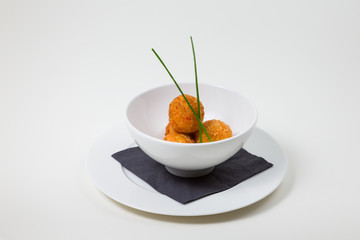 Fried balls in a white bowl on a white plate on a white background isolated