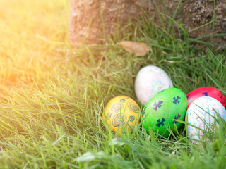 Colorful Easter eggs in grass against blurred green background with small house model on back side.  Spring holidays concept